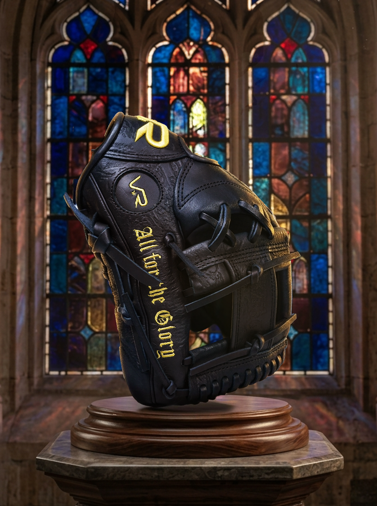 A black leather VROBI "All for the Glory" baseball glove displayed on a tiered wooden and marble pedestal. The glove features prominent gold embroidery on the thumb reading "All for the Glory" in a gothic-style font, along with a gold "VR" logo. The leather is covered in intricate, tonal floral and religious engravings. In the background, a large, arched stained-glass window with blue, red, and yellow panels is softly lit, creating a cathedral-like atmosphere.