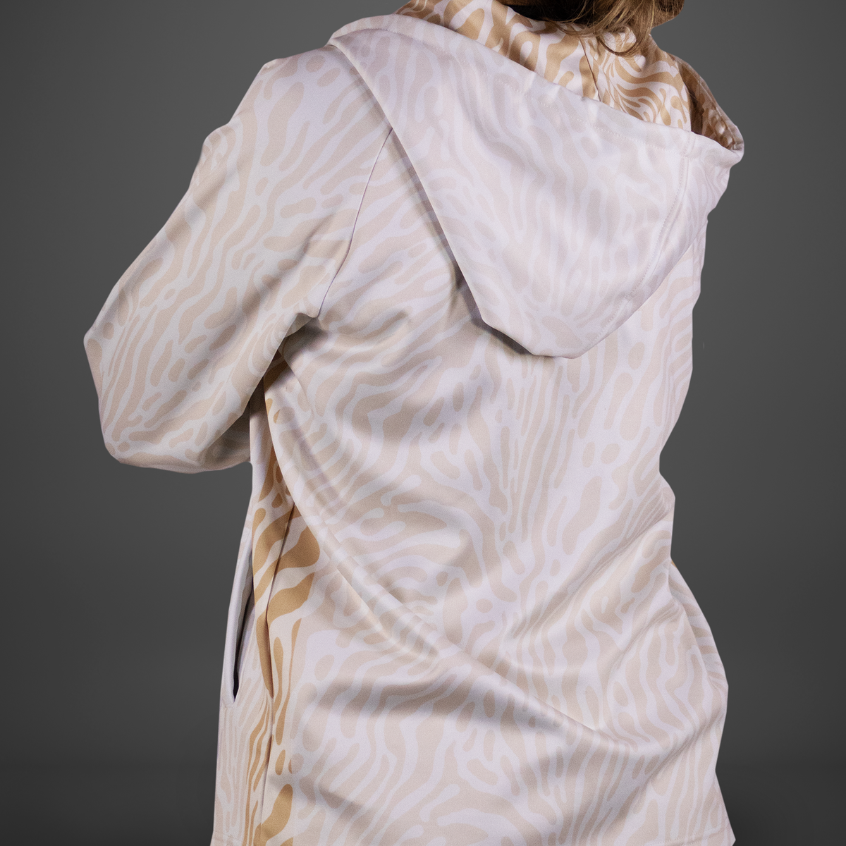 Person wearing a patterned coat with a hood on a gray background